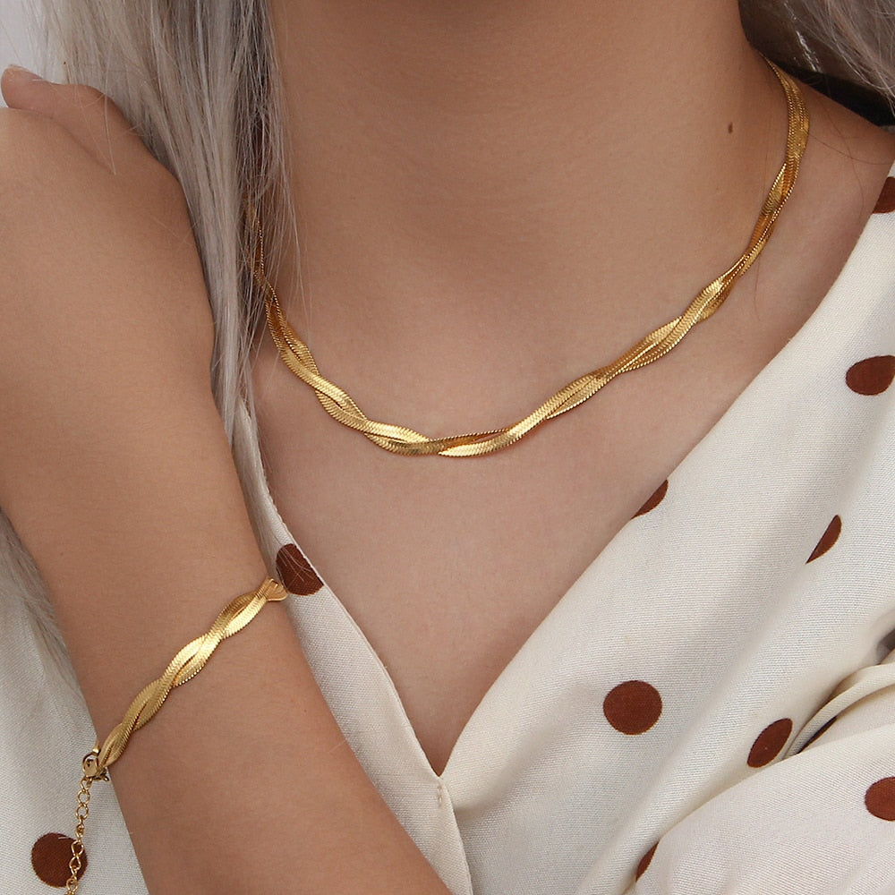 18K gold plated herringbone chain necklace and bracelet set with sleek, shiny finish, styled on a neutral background.