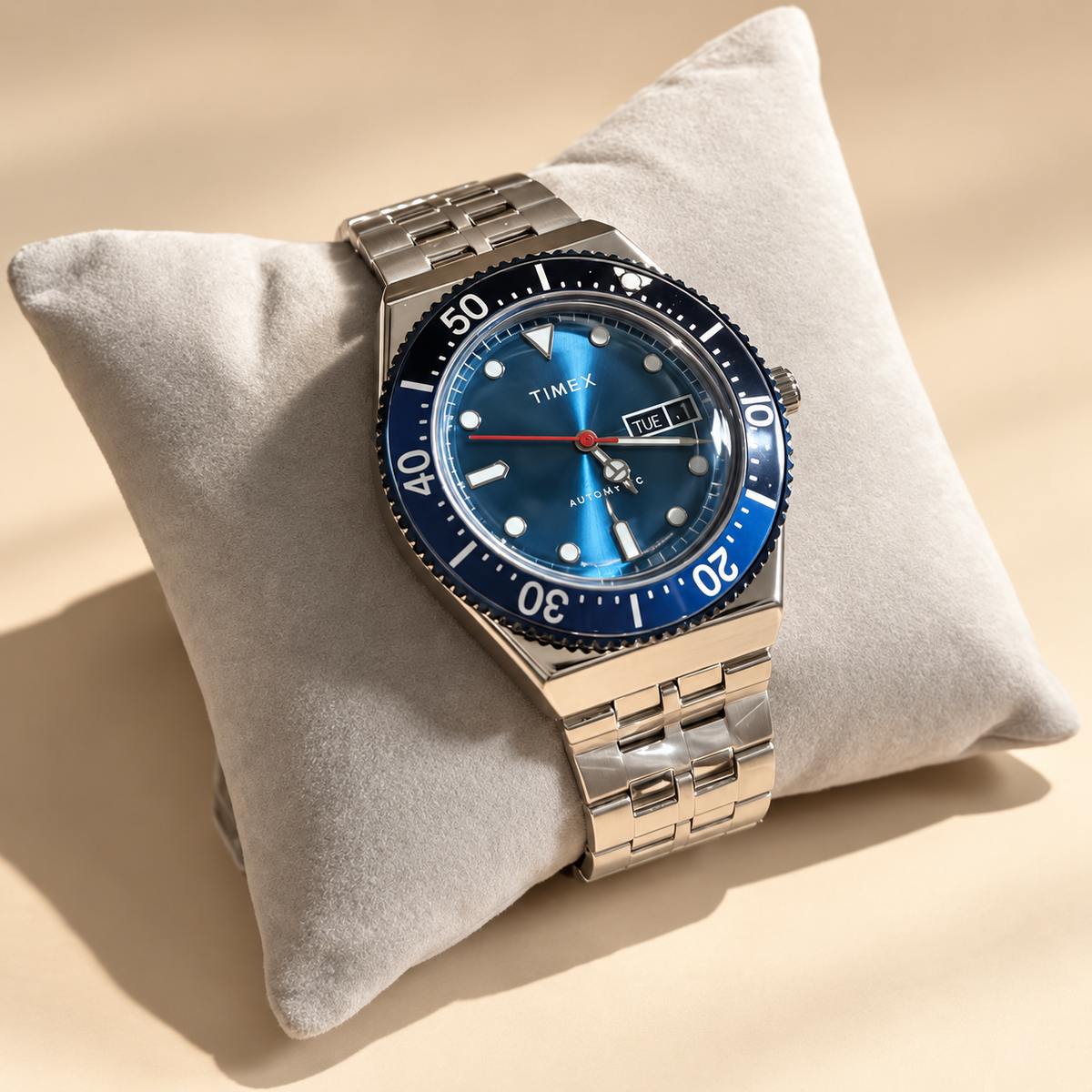 Ticora Timex automatic stainless steel diver watch displayed on a velvet cushion with a black dial and rotating bezel.